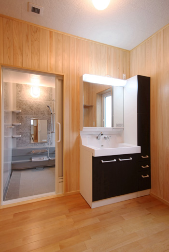 洗面脱衣室です。木材の壁に白と黒の洗面台は良いアクセントとなりおしゃれです。